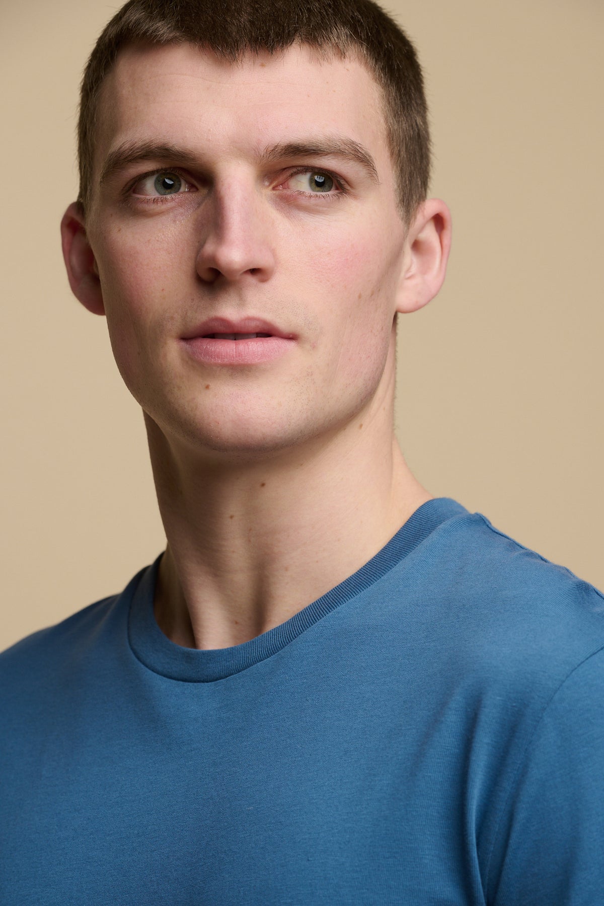 Portrait of brunet male wearing crew neck, short sleeve t shirt in RAF blue