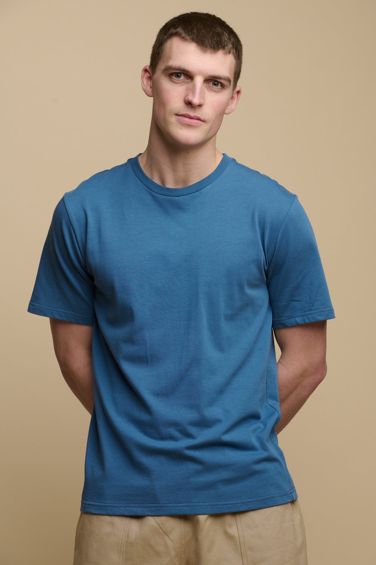 Thigh up image of brunet male wearing short sleeve crew neck t shirt in RAF blue