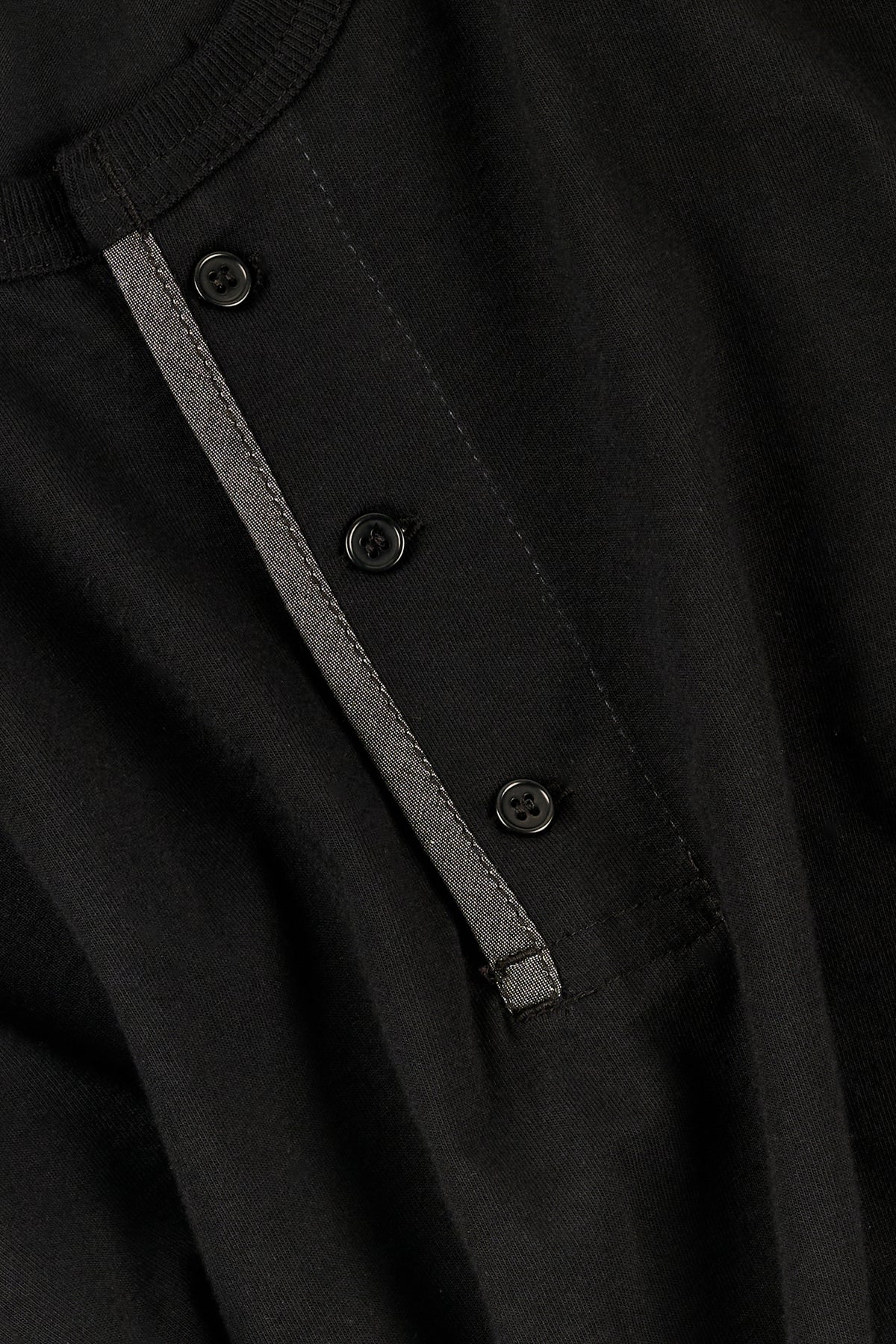 Close-up of a black henley with buttons and a striped trim