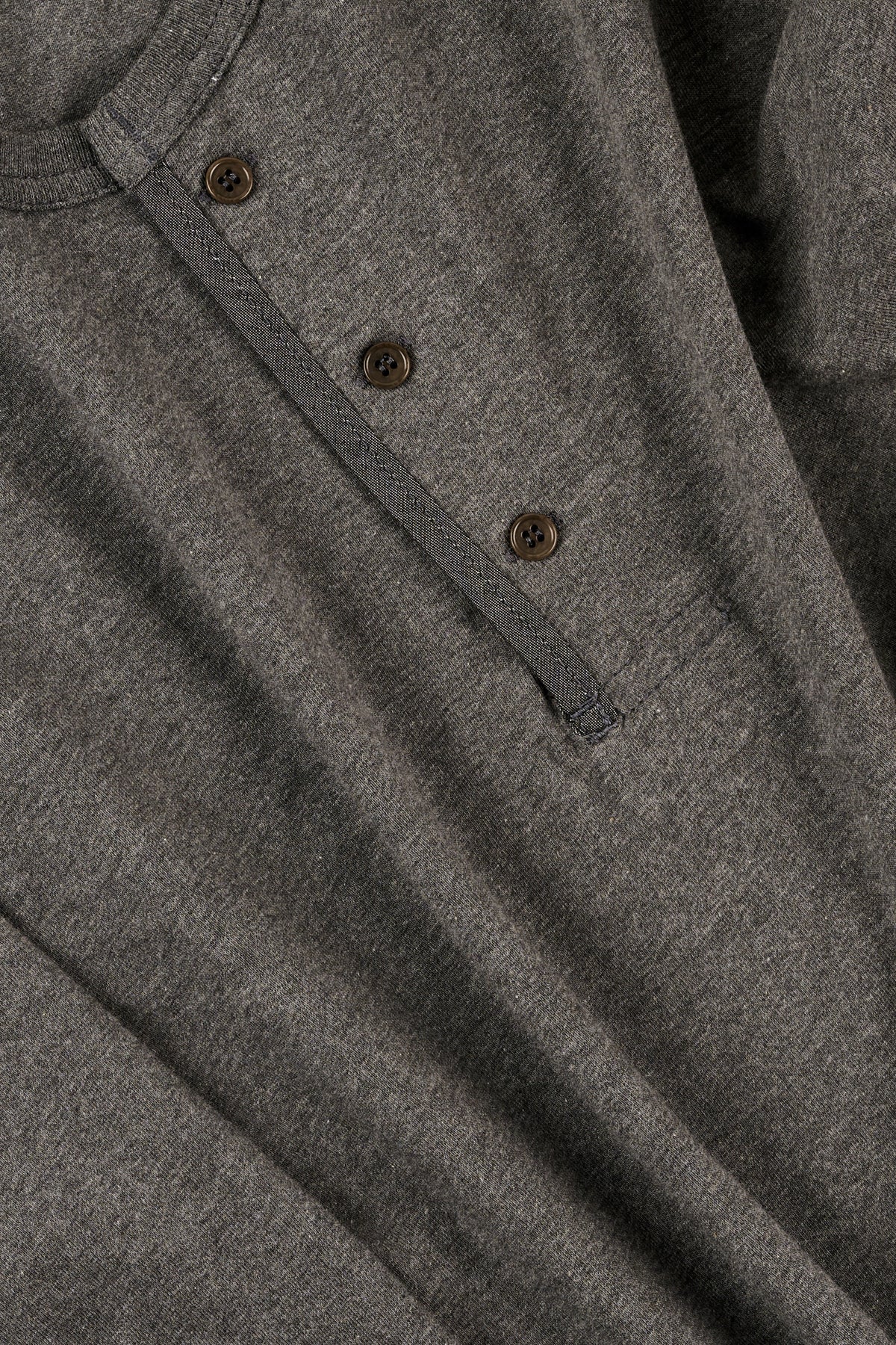 Close-up of a grey henley with buttons on a plain background