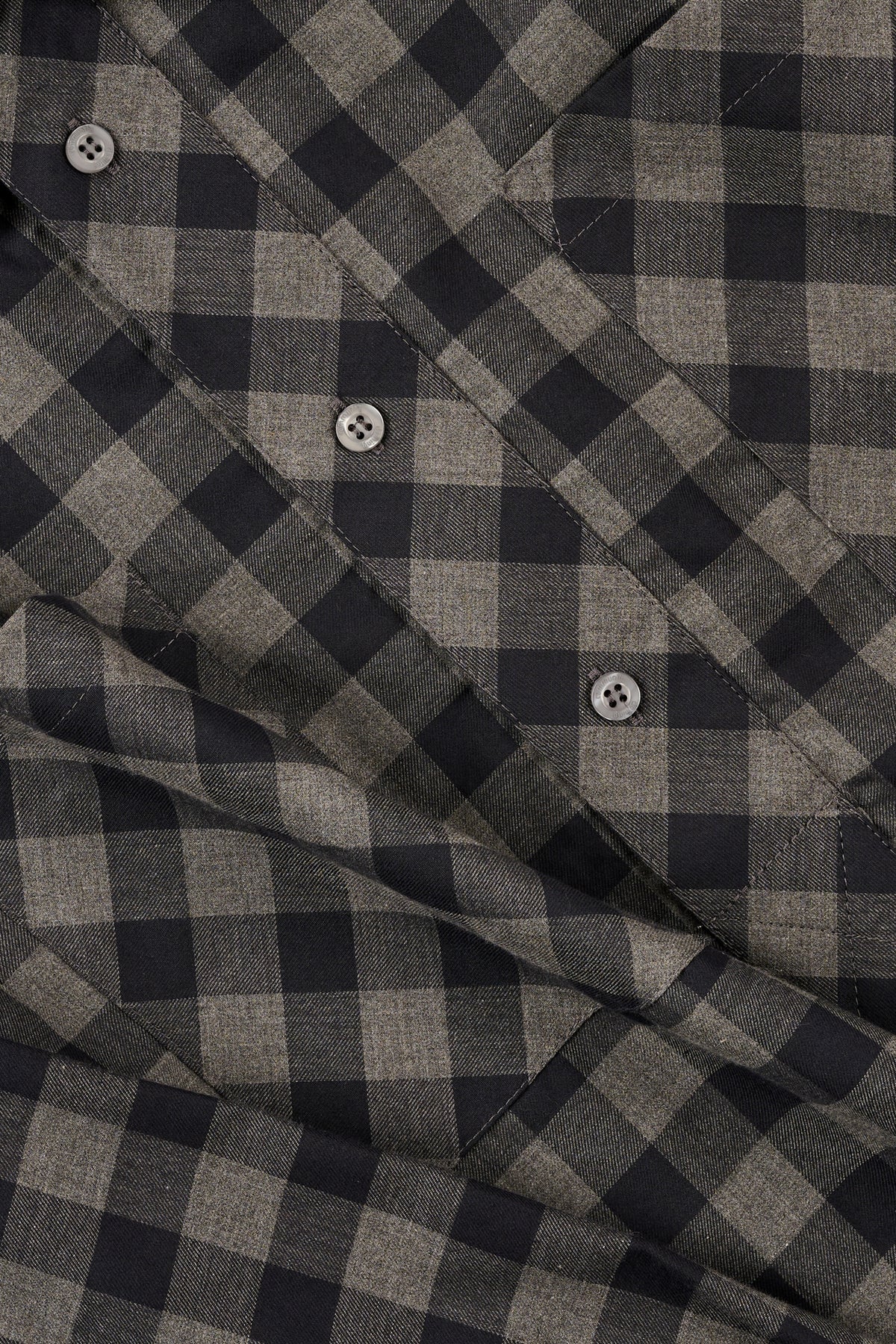 Close-up of a grey and navy checkered fabric with buttons.