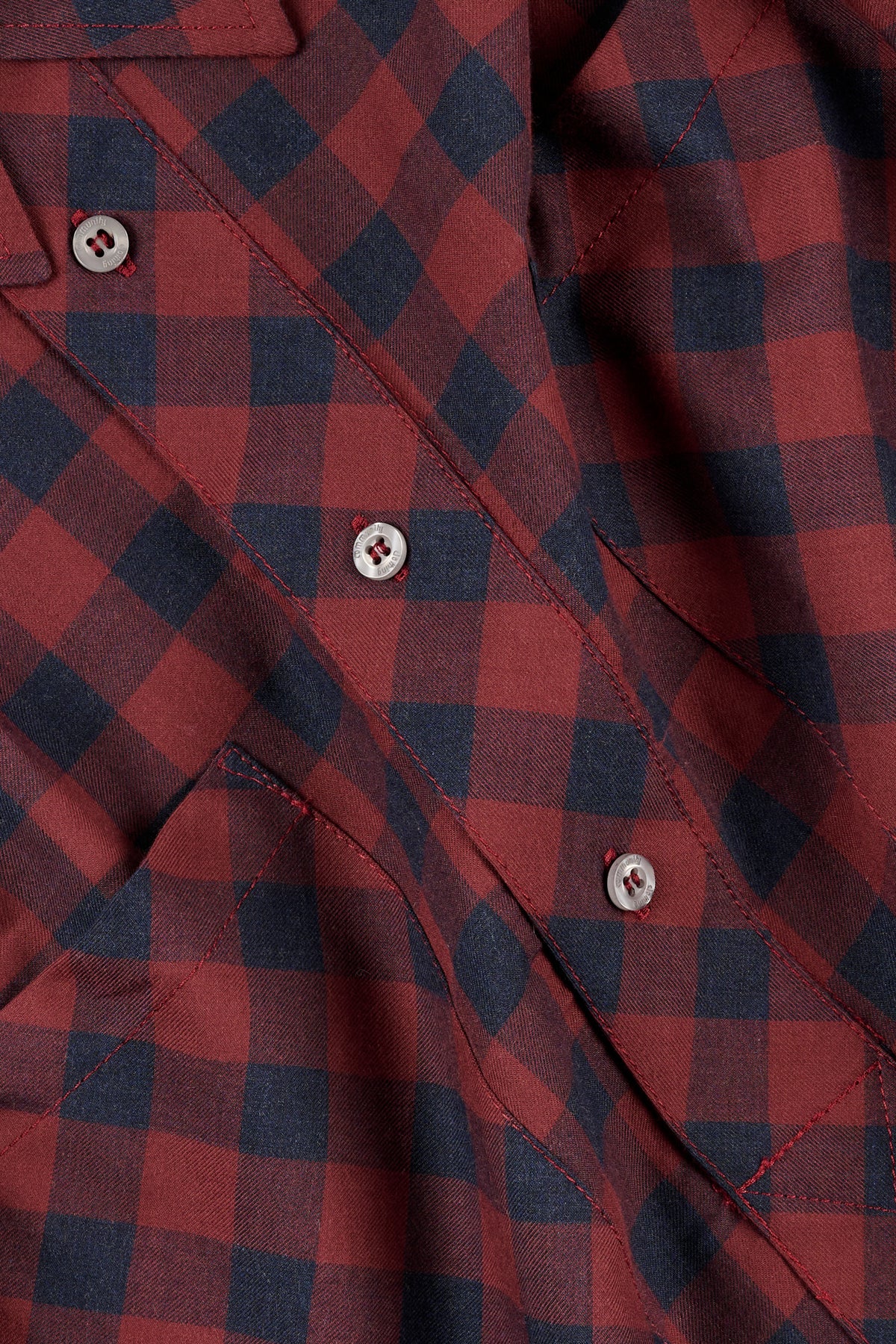 Close-up of a red and navy checkered shirt with buttons.