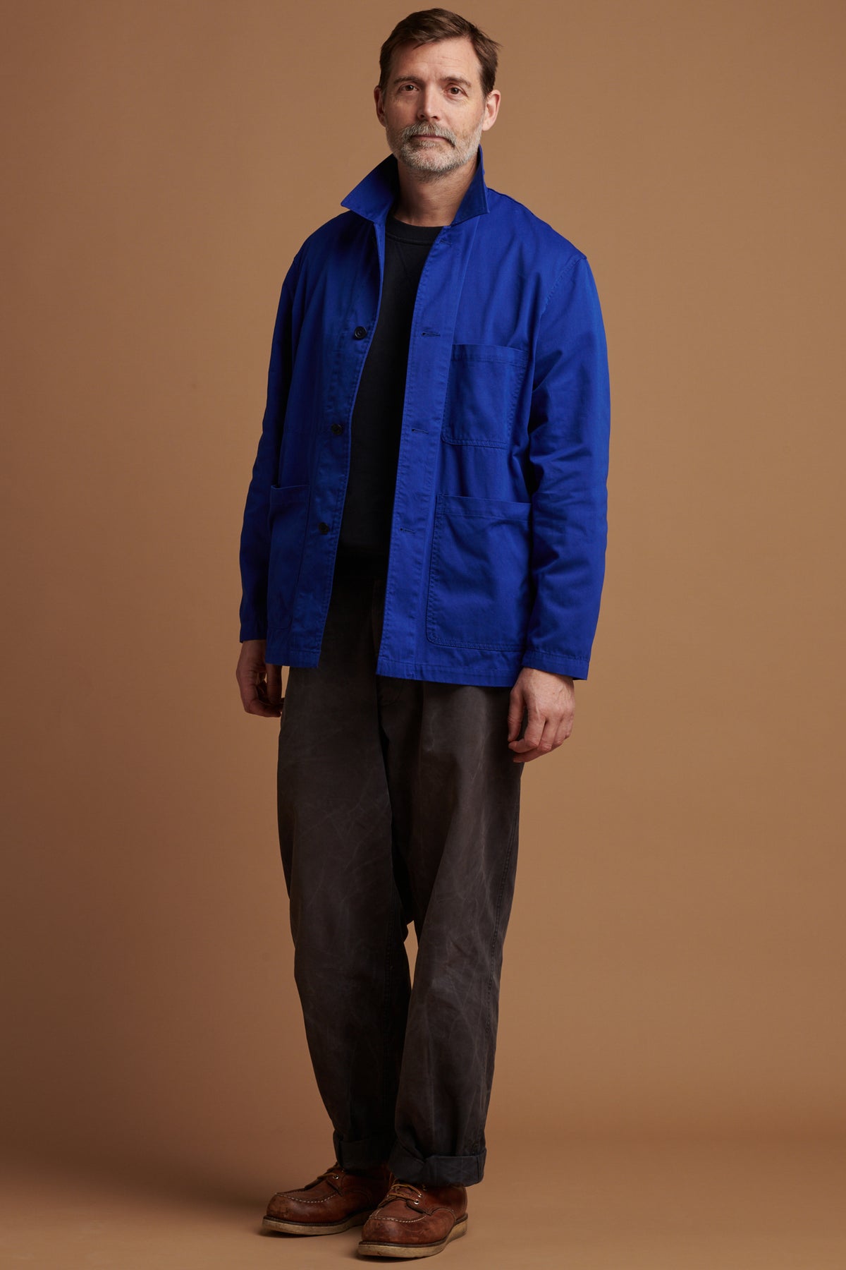 The front of Patrick Grant wearing Community Clothing Chore Jacket in Royal Blue unbuttoned over navy heritage sweatshirt