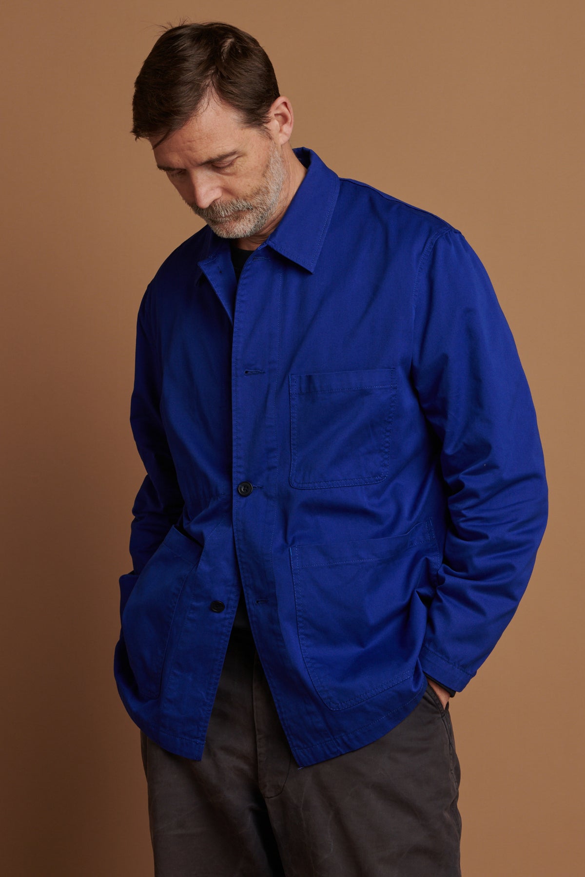 Thigh up image of Patrick wearing chore jacket in royal blue 