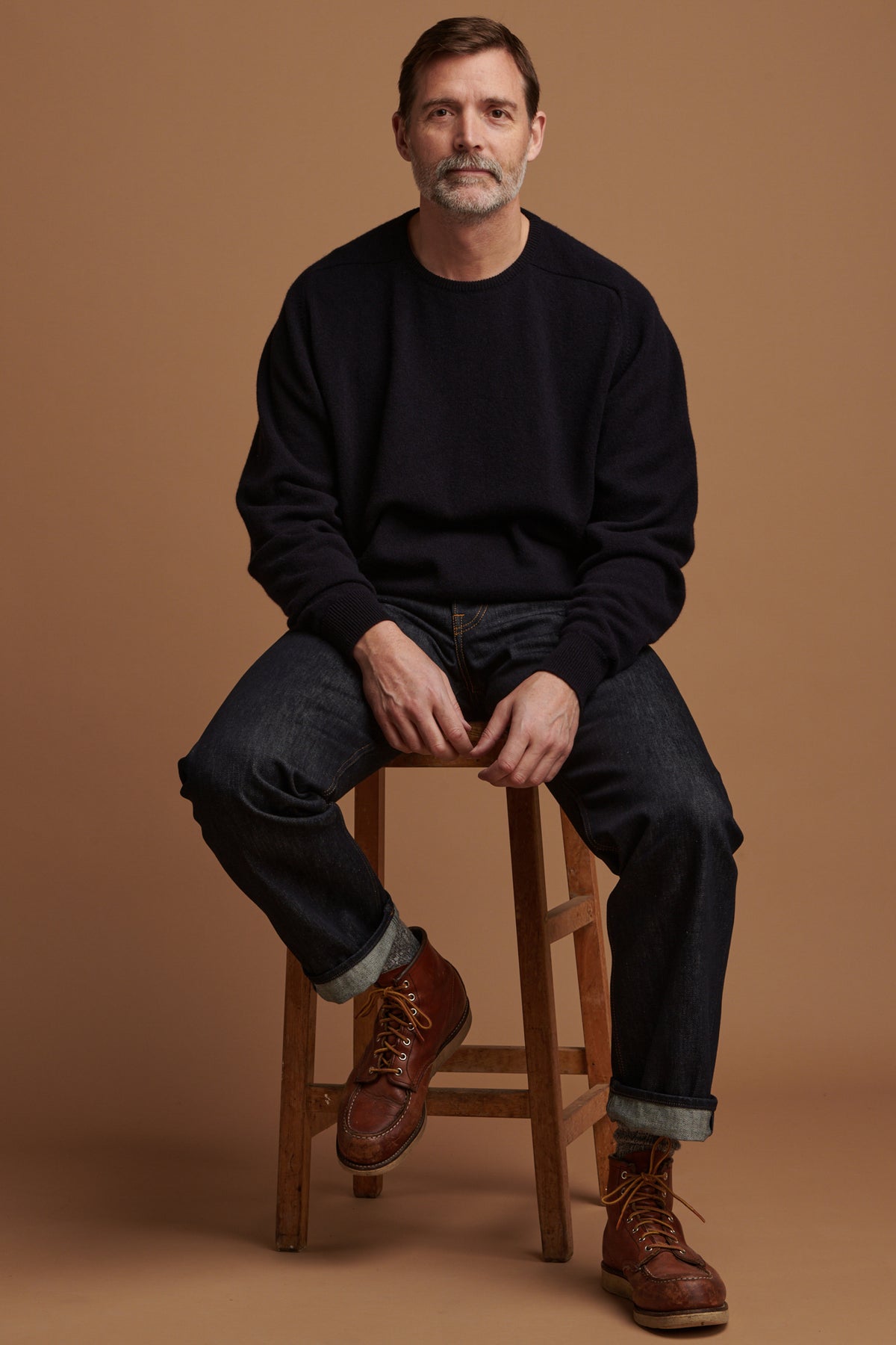 Patrick Grant wearing lambswool saddle shoulder crew neck jumper in navy paired with loose fit button fly Arran jean in indigo