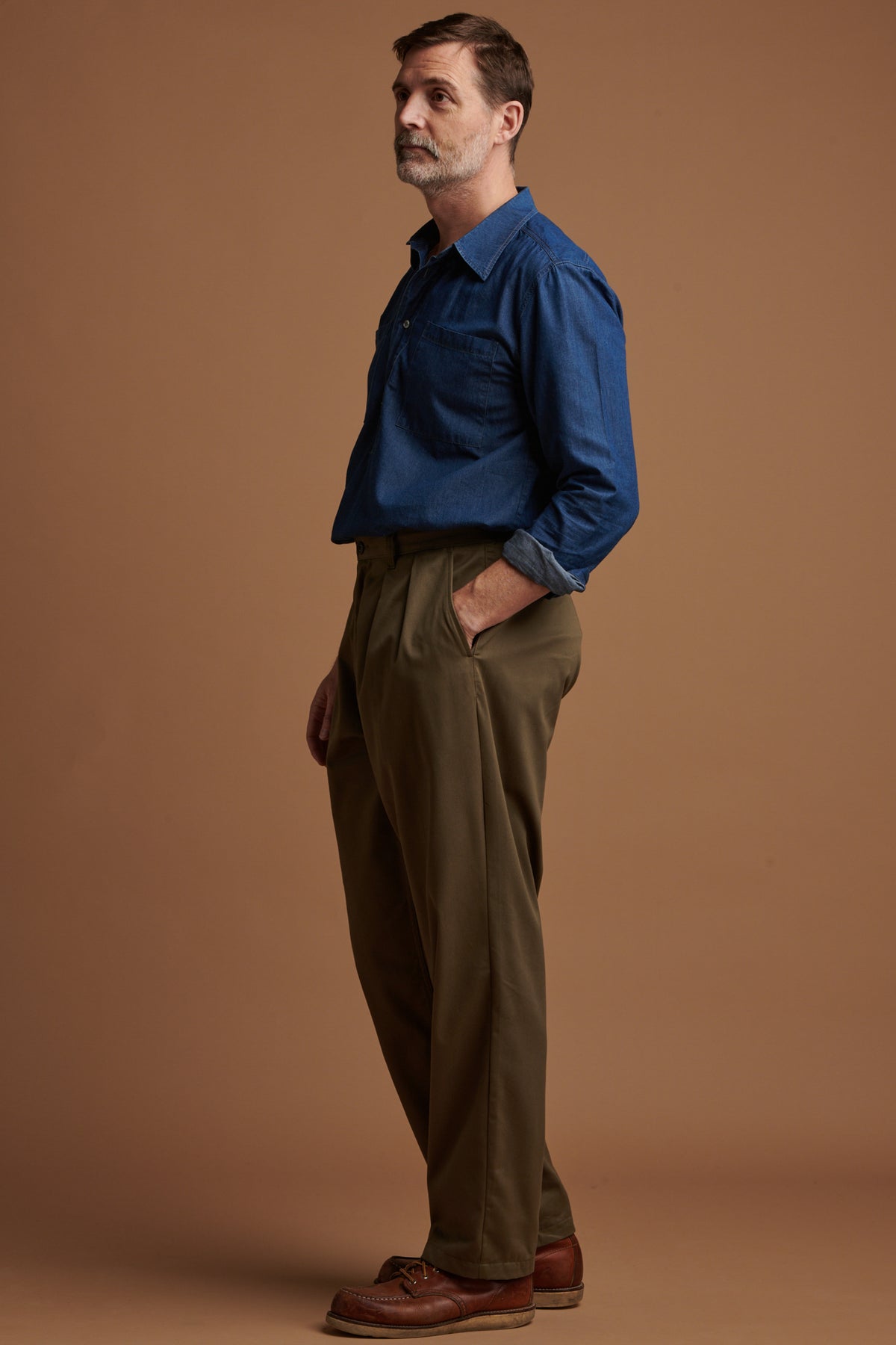 Patrick Grant wearing Community Clothing pleated cotton chino in olive with lightweight denim Oli shirt tucked in