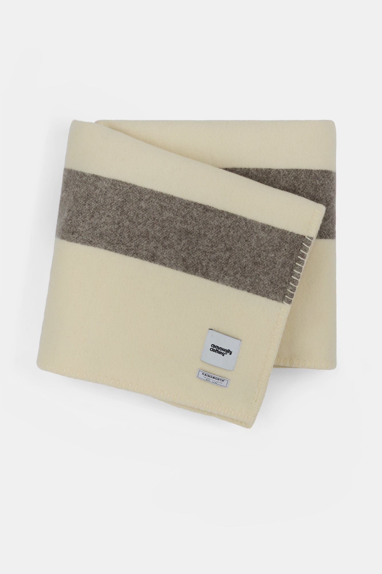 Blanket in ecru dark brown and tan stripe with Community Clothing woven logo in the bottom right hand corner.