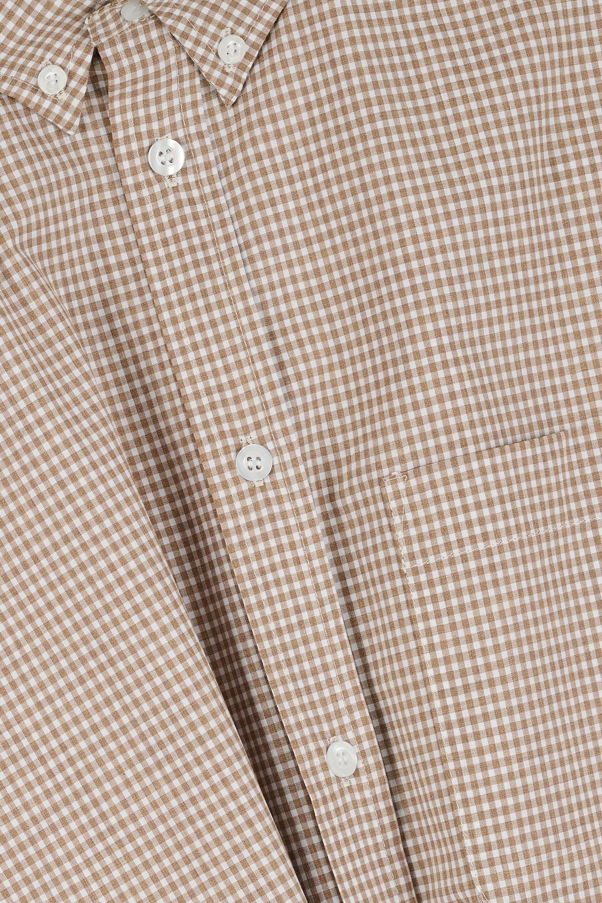 Close-up of a brown and white checkered shirt with buttons.