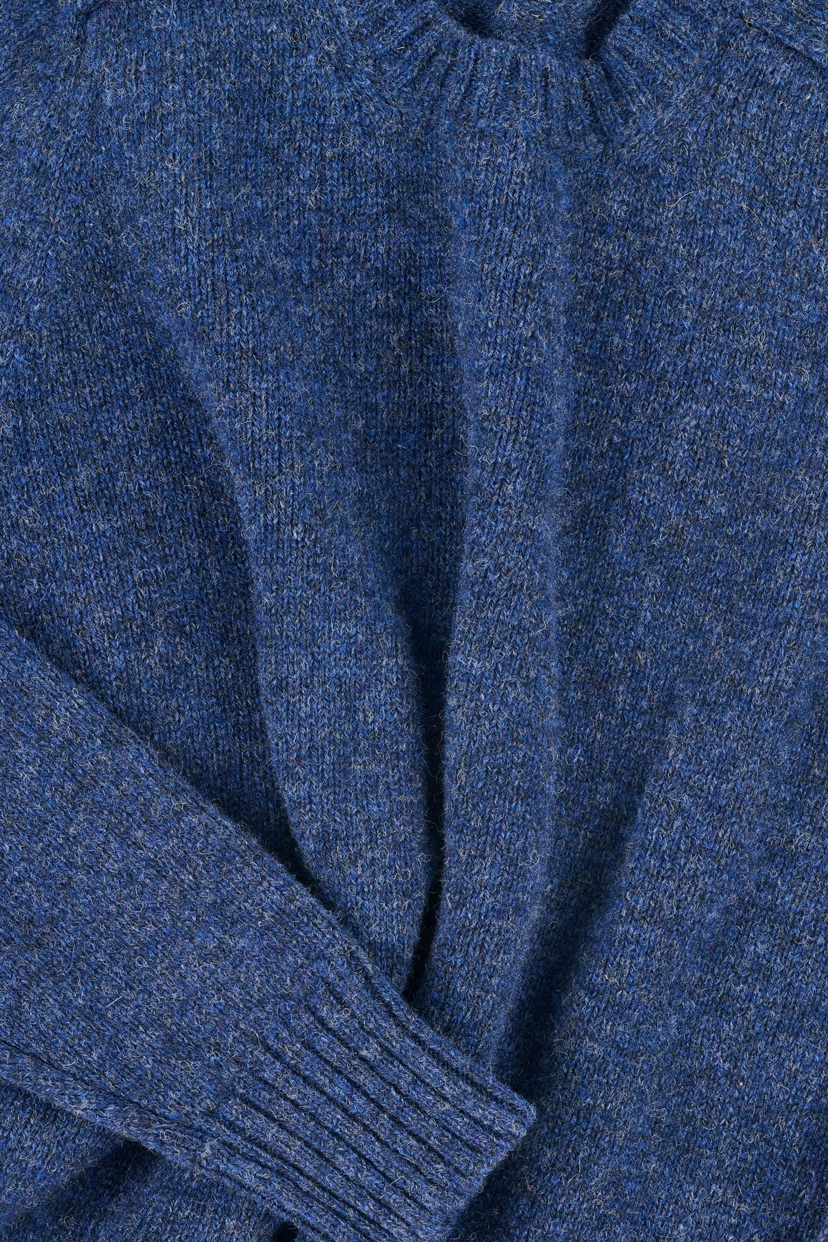 Close up of a blue knitted sweater with a focus on texture and colour.