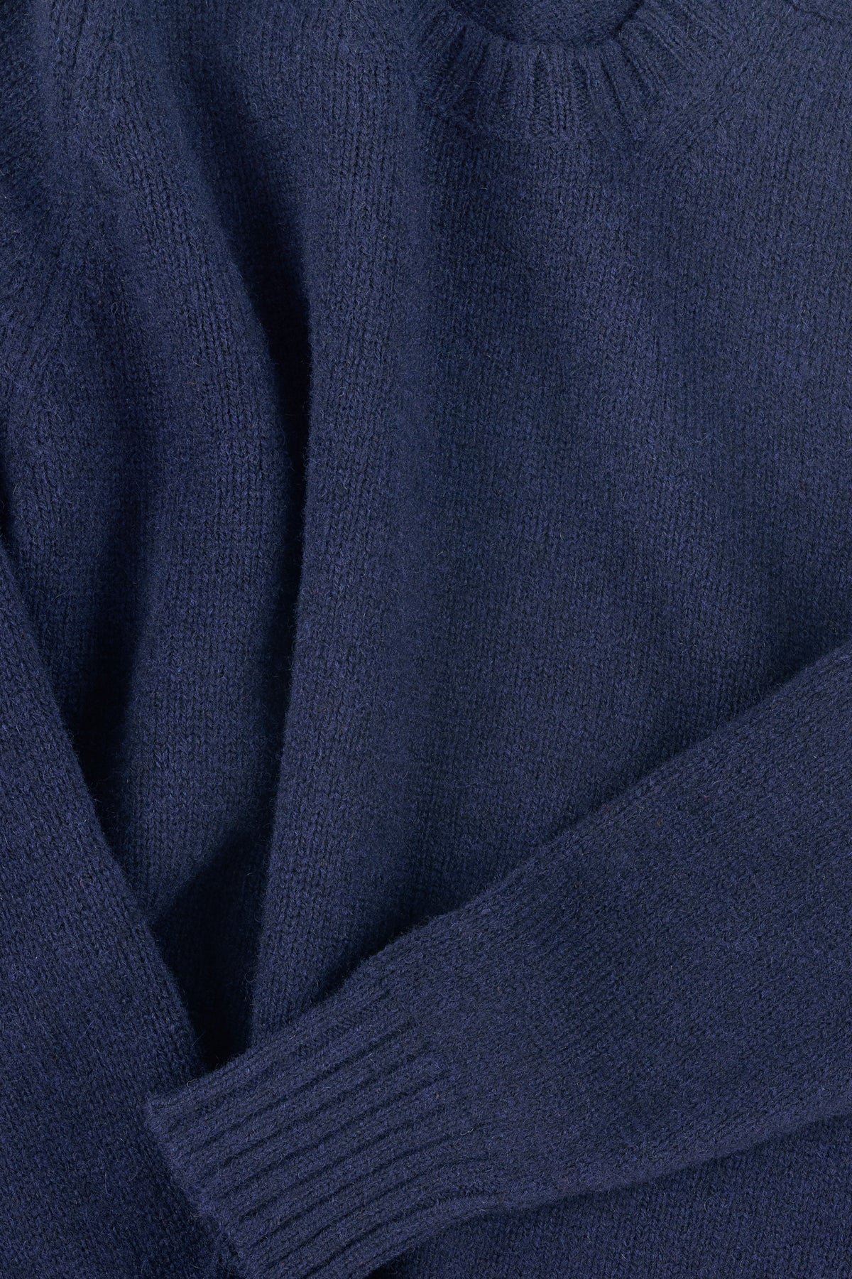 Close up of navy shetland knit sweatshirt with ribbed neckline and cuff.