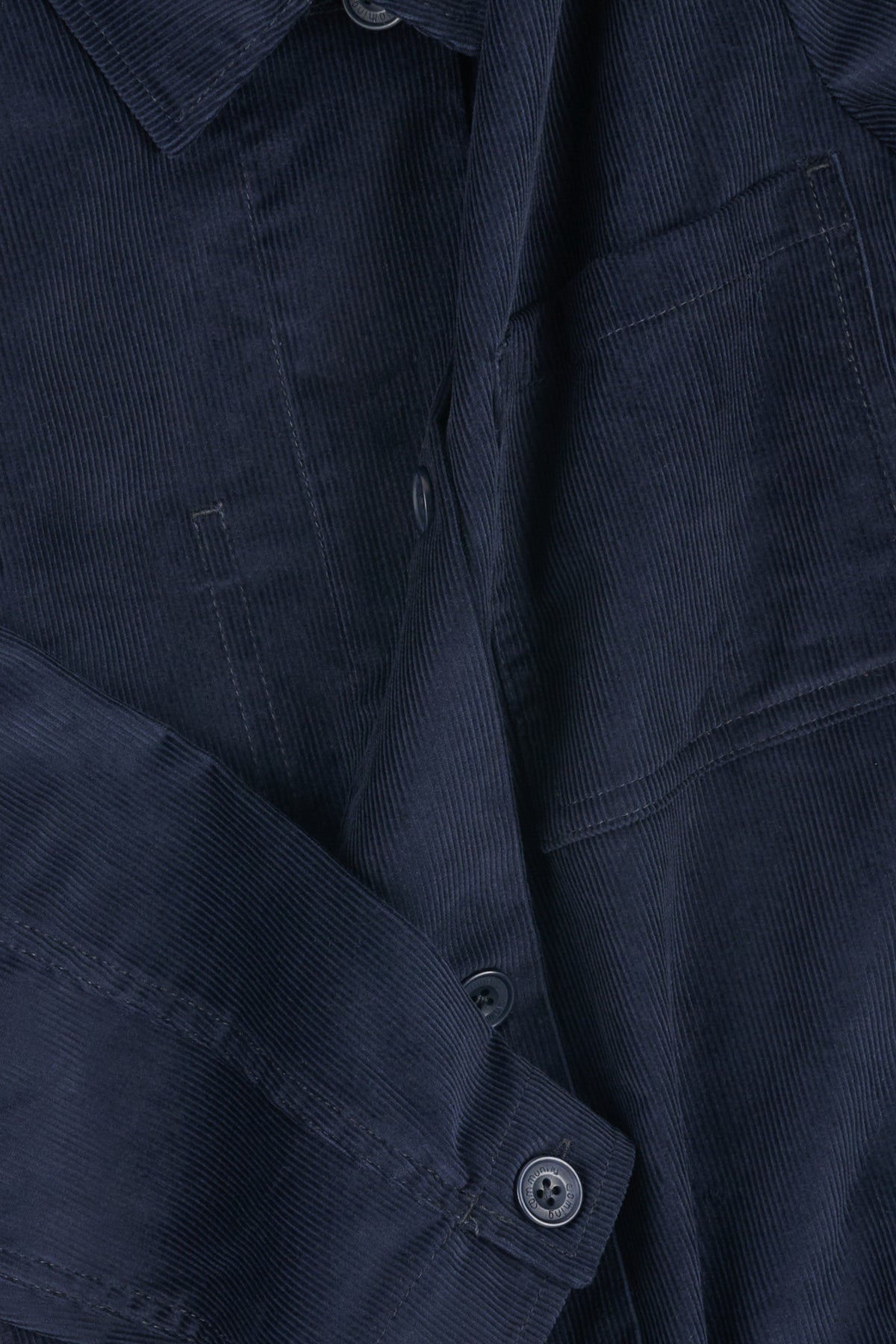 Close-up of a navy blue corduroy overshirt with buttons.