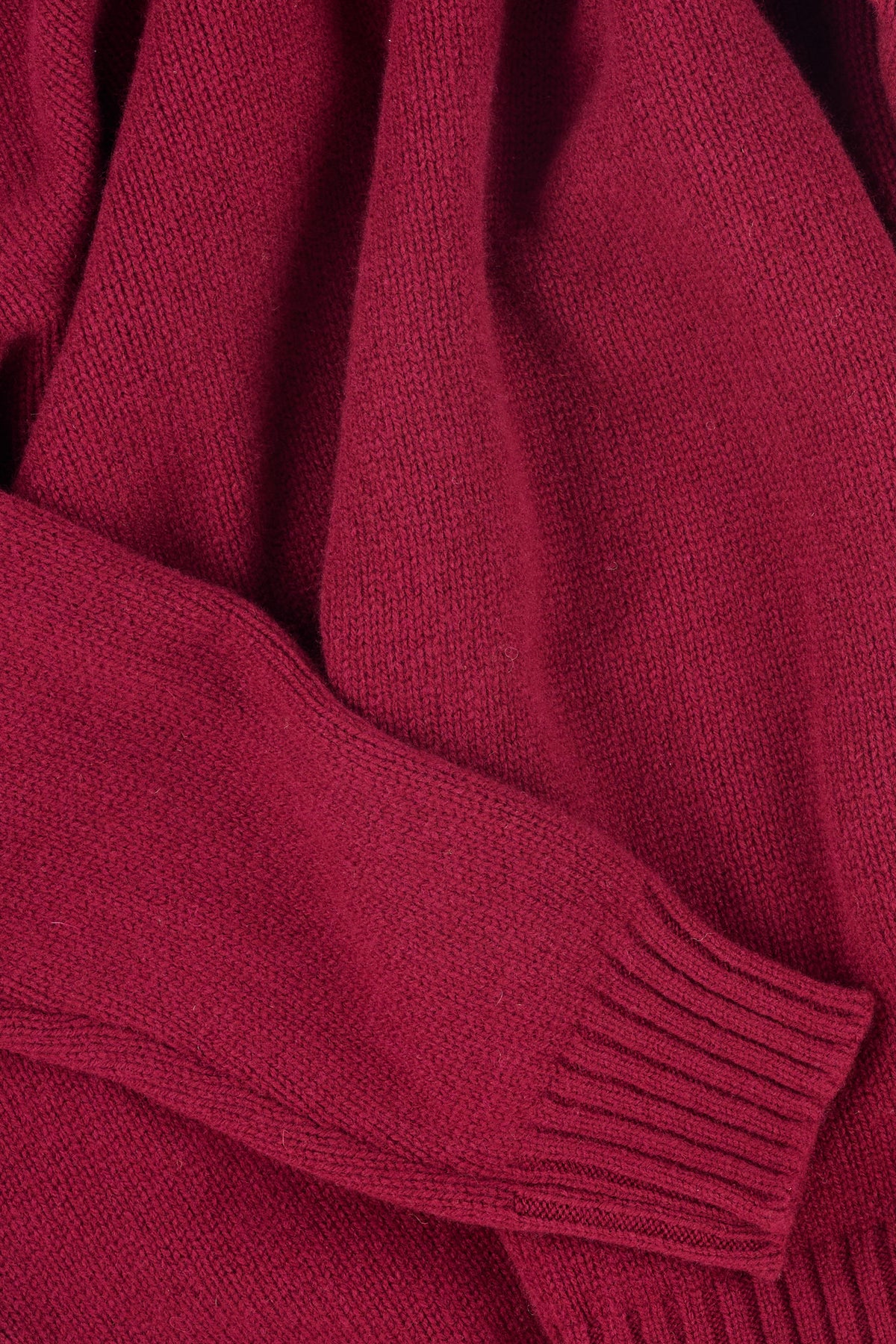 Close up of burgundy knit jumper with ribbed hem and cuff.