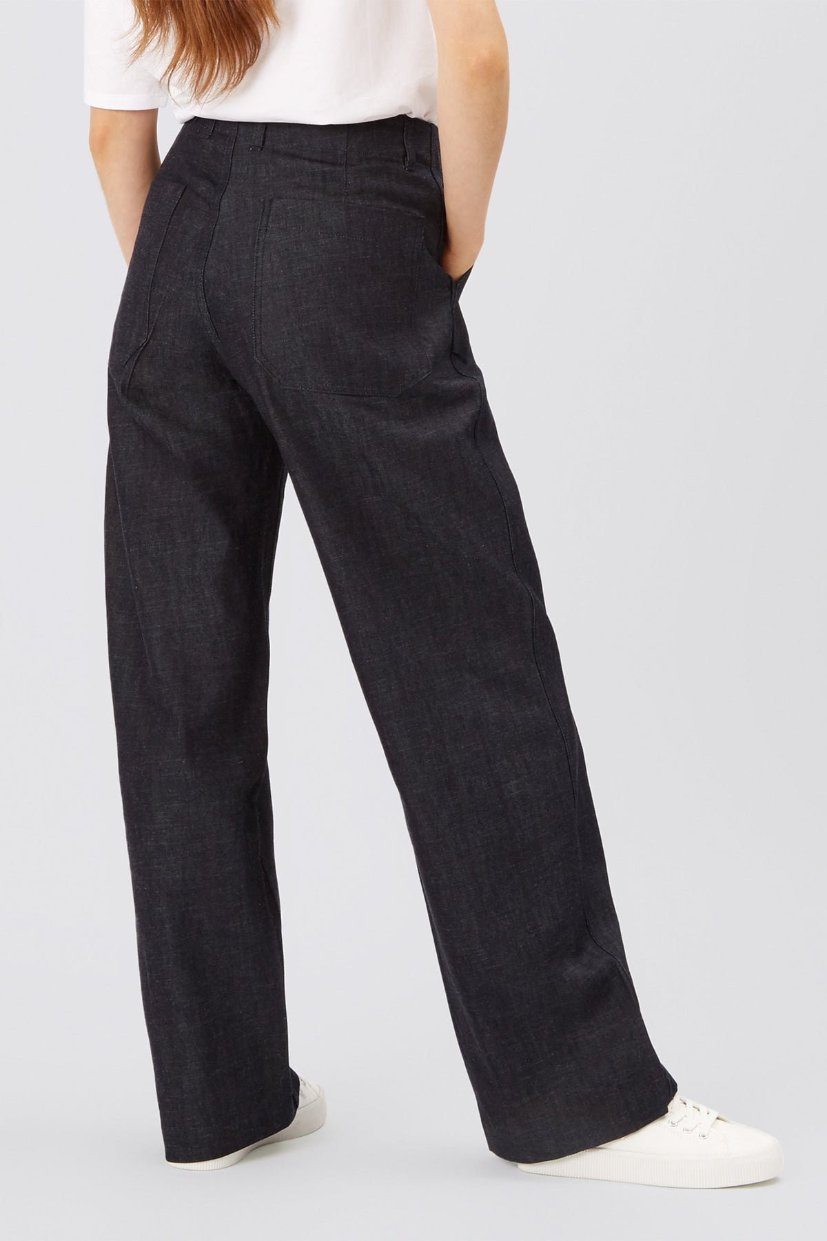 The back of female from tbelow the shoulders down wearing work trousers in indigo denim.